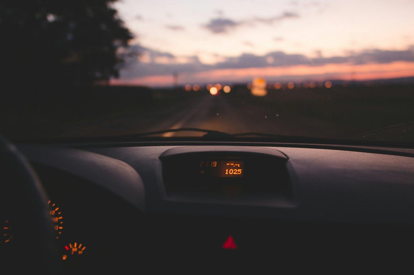 Dashboard glowing at dusk with a warning light